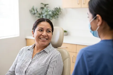 Patient smiling as she talks with a dental assistant
